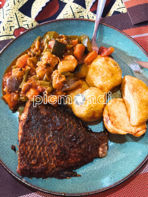A dish of food, made with potatoes, vegetables and fried fish